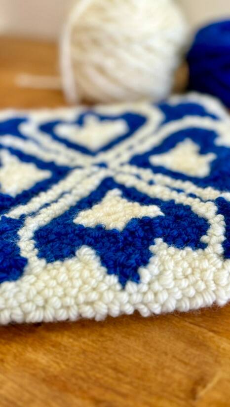 Detalhe de um azulejo azul e branco, com novelos de lã ao fundo