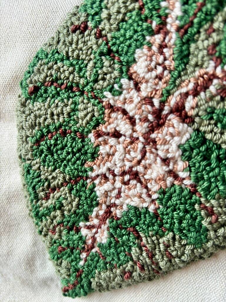Detalhe dos pontos verdes e cor-de-rosa de uma folha bordada