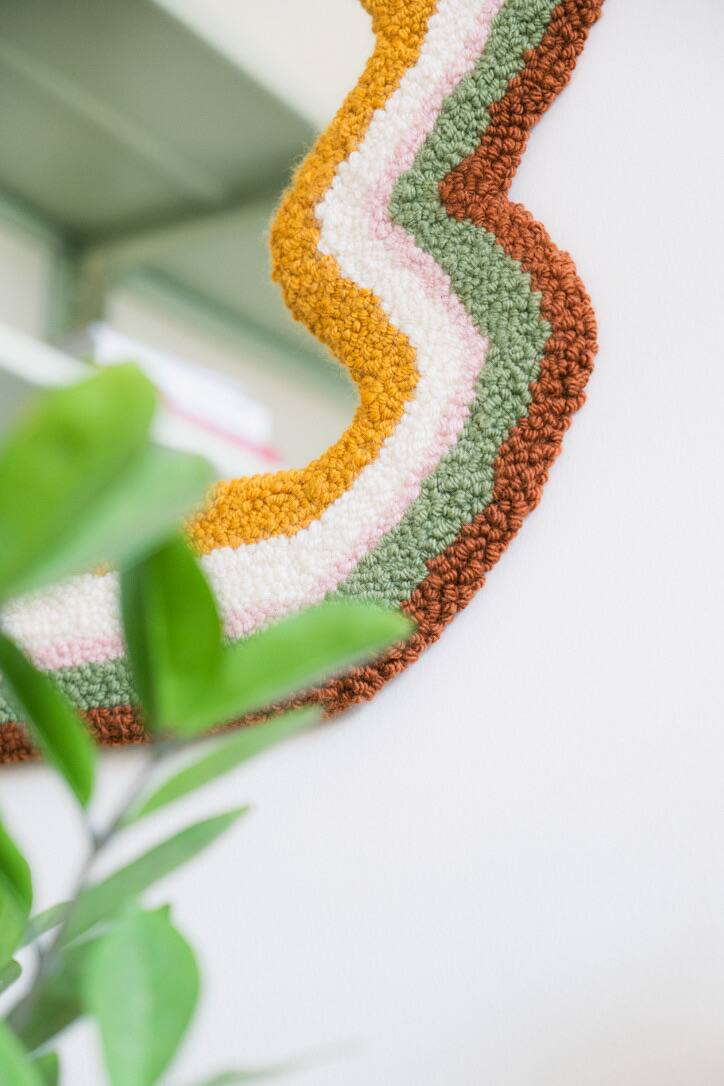 Detalhe da moldura de um espelho em punch needle, faixas amarelas, creme, verdes e marrons