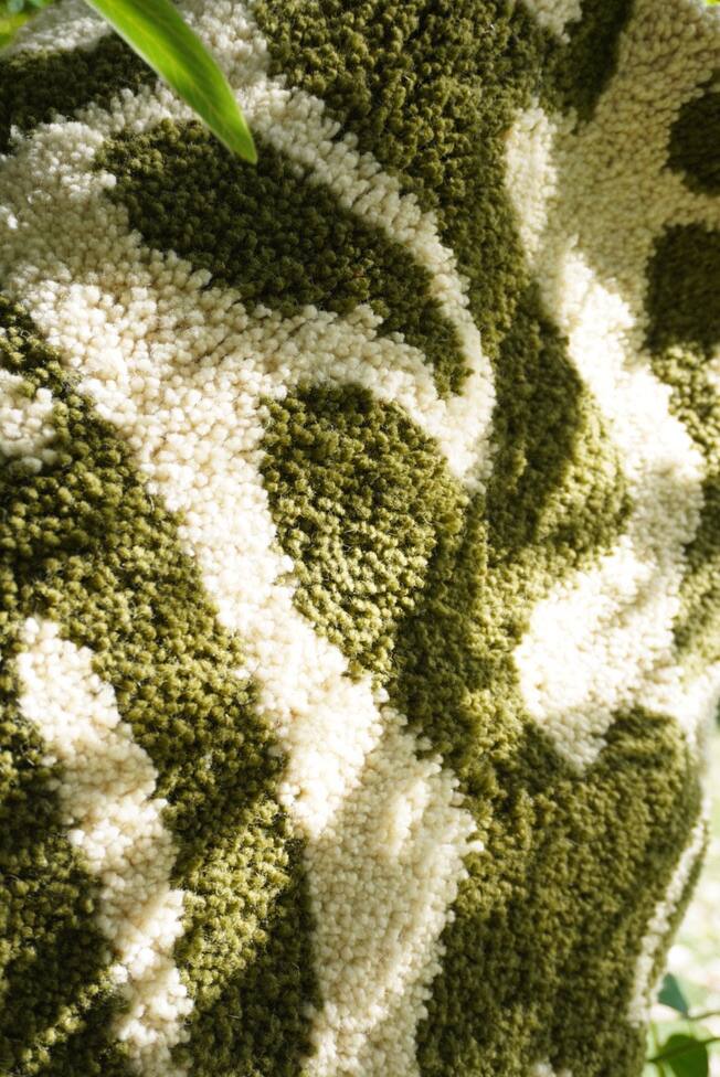 Detalhe de uma peça em tufting, lã verde e creme